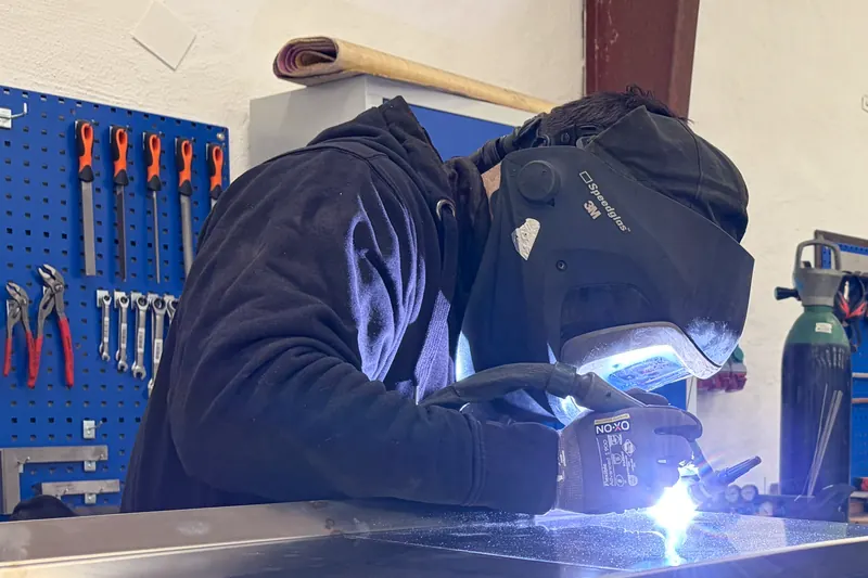 Svejser i arbejde ved bordet i Velmos smedeværksted